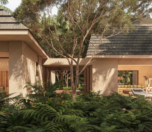 A tan villa in the jungle with an open sliding glass door and a woman standing outside on the pool deck.