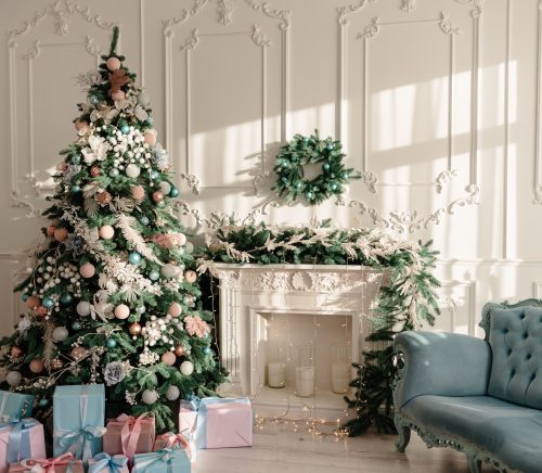 A Christmas tree decorated next to a fire place and a couch.