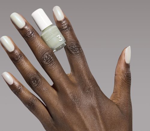 A hand with painted nails holding a nail polish bottle.