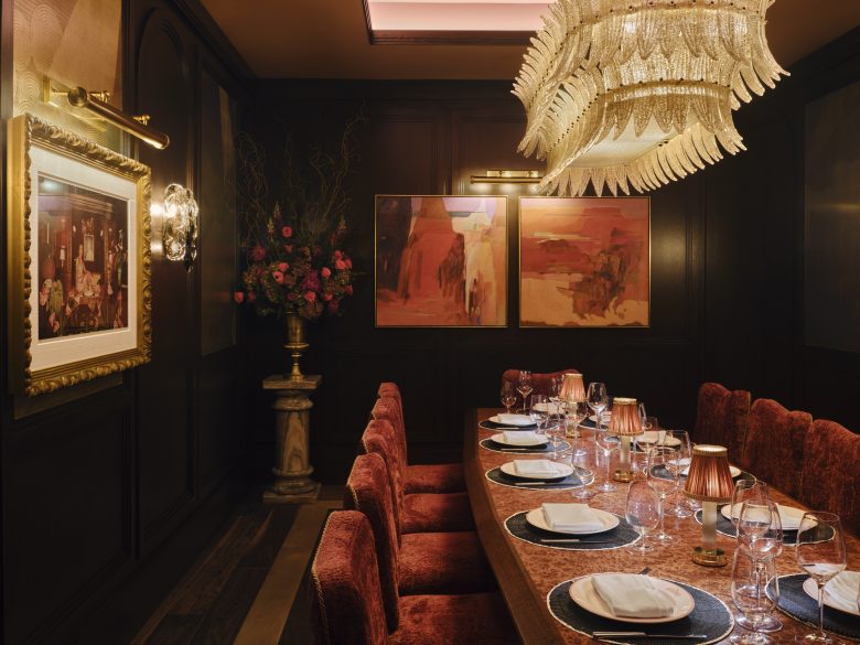 A low lit dining room with a long table.