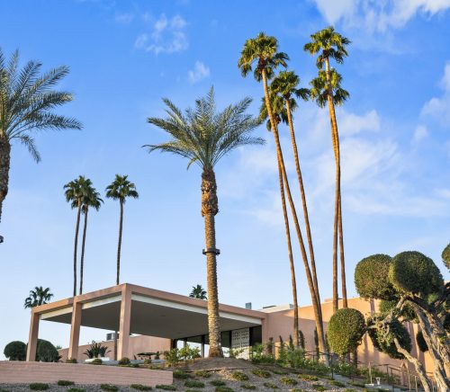 Marrakesh clubhouse, which is painted pink, surrounded by tall palm trees.