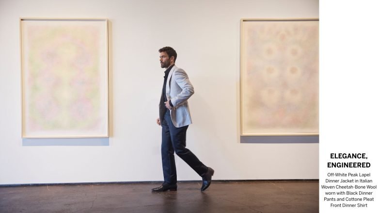 A man walks between two pieces of hanging artwork.